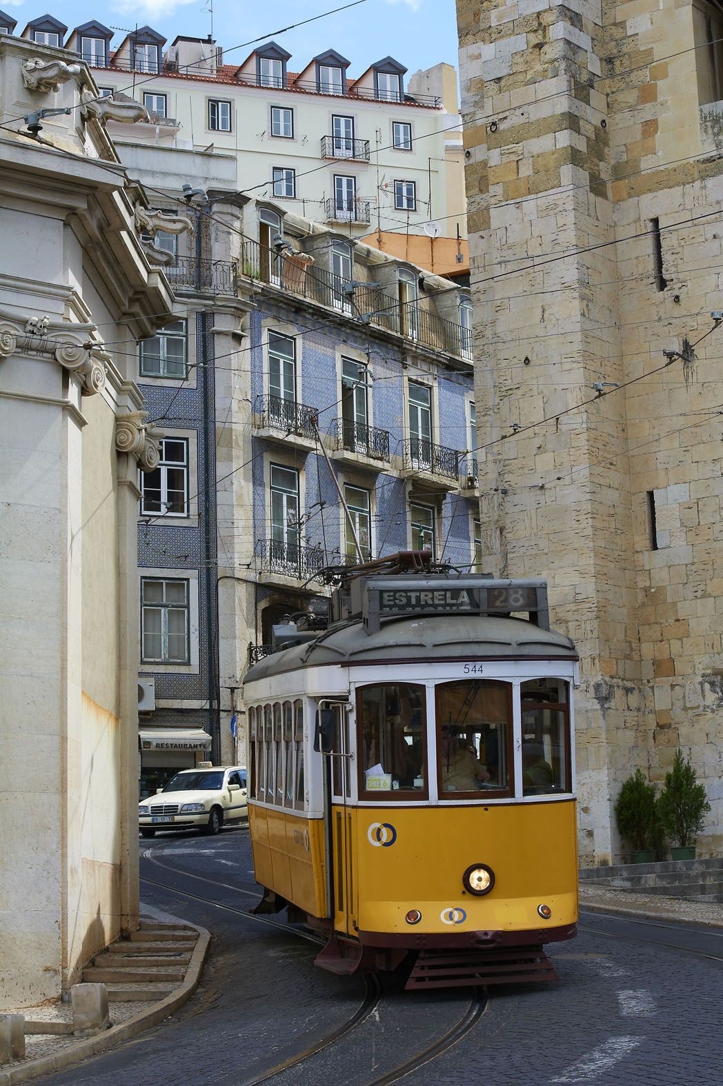 Yellow tram on a Lisbon street, between tiled facades and stone buildings